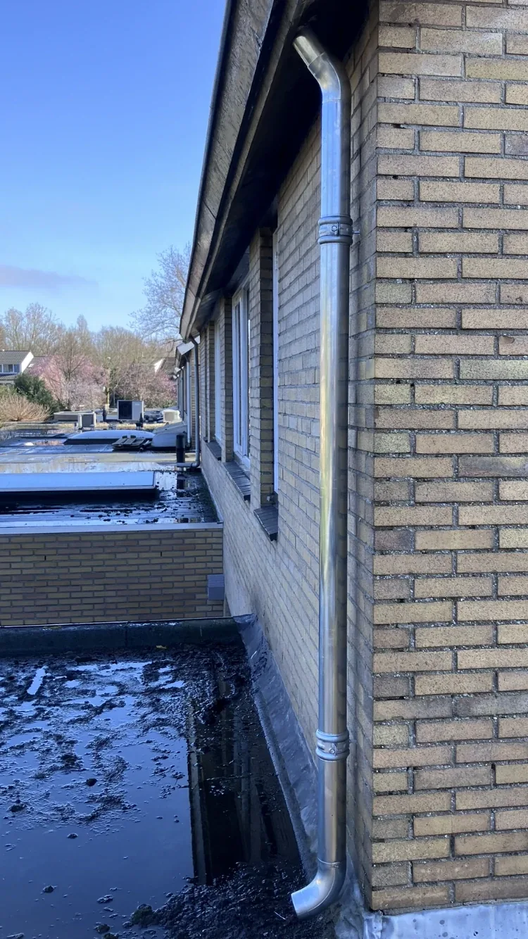 Nieuwe zinken regenpijp aan de gevel